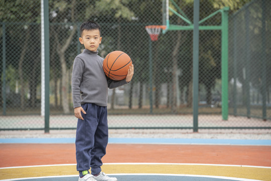 操场上抱着篮球的少年