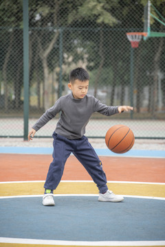 学校操场上打篮球的小男孩