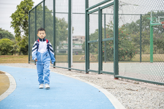 走在球场旁边路上的小学生