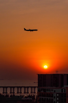 夕阳下准备降落的飞机剪影