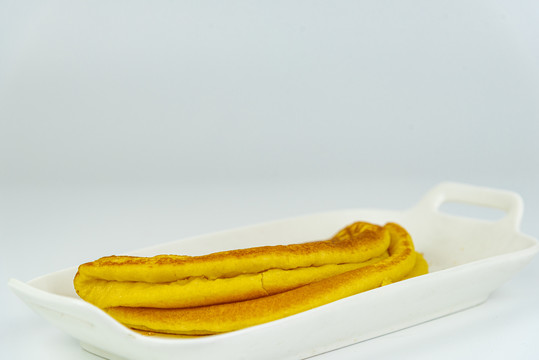白色盘子里的黄色小米面煎饼