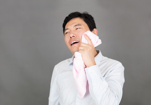 牙痛的男士用毛巾热敷脸部