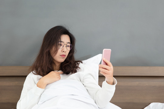 女子玩手机坐在床上