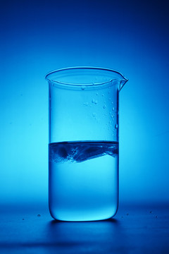 蓝色背景下的水杯与冰块