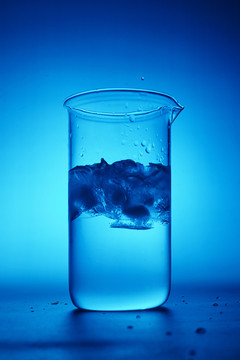 蓝色背景下的水杯冰块与飞溅