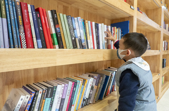 男孩站在书架前挑选书本