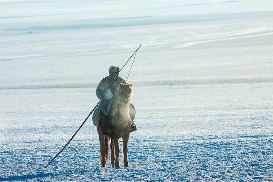 冬季雪原蒙古族骑马套马杆
