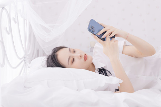 在床上玩手机的年轻女性
