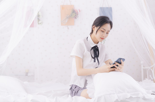 在床上玩手机的年轻女性