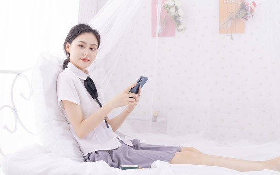 床上玩手机的年轻东方女性