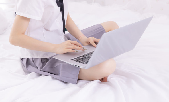 女孩在床上使用笔记本电脑