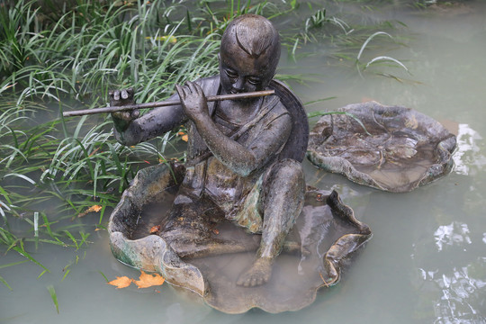 水中坐荷叶吹笛子的男孩雕像