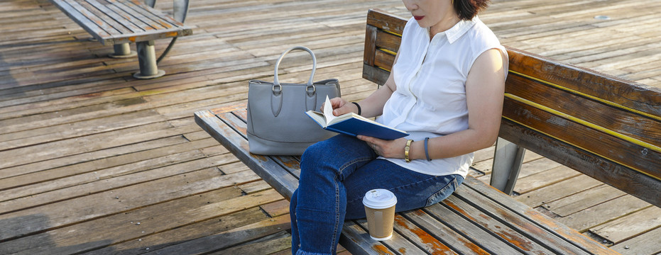 坐在户外长椅看书阅读的女人