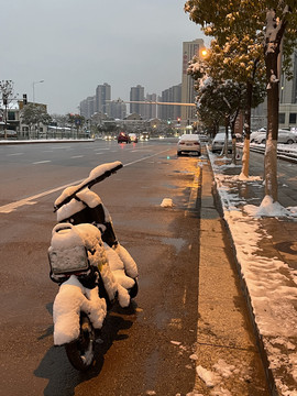 马路边背雪覆盖的共享电动车