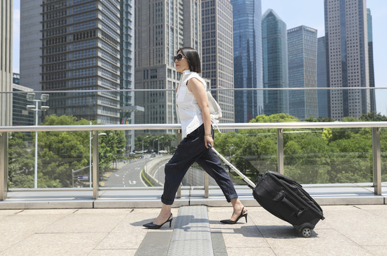 商务女士手拉旅行箱走在街道