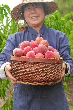 女人手上抱着一筐胭脂红桃子