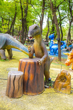 倚树墩立着的恐龙腊雕像