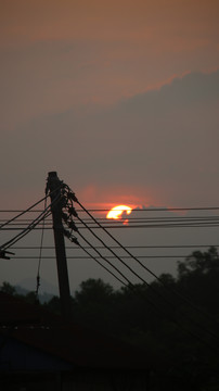 电线杆下云朵后躲藏的夕阳