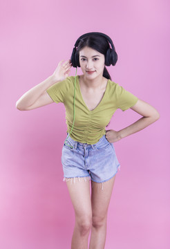 粉色背景里戴着耳机的亚洲美女
