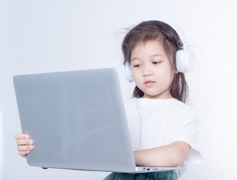 戴耳麦使用电脑的小女孩