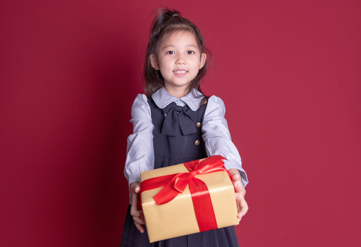 小女孩学生装扮拿着礼物盒