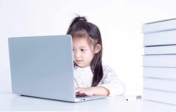 书桌上使用电脑学习的小女孩