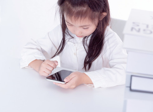 书桌上使用手机的小女学生