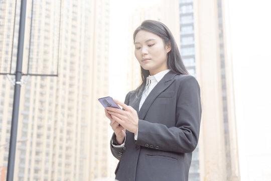 街头使用手机的西装女性