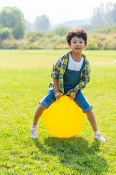 一个小男孩在草地上玩球