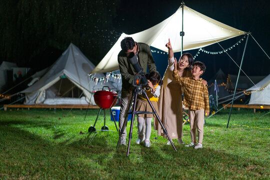 傍晚一家人在露营地用望远镜看星空