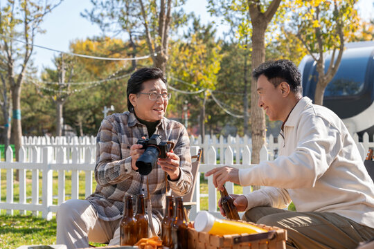 两个老年男人坐在露营地看数码相机