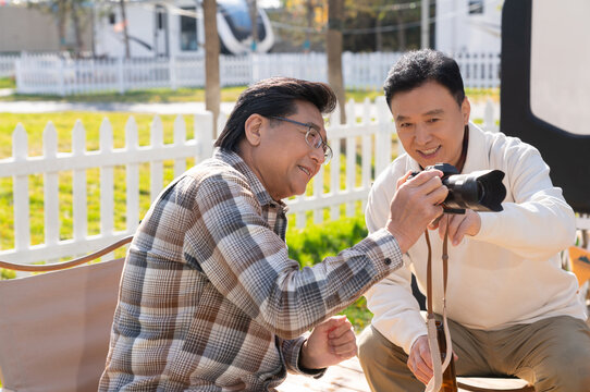 两个老年男人坐在露营地看数码相机