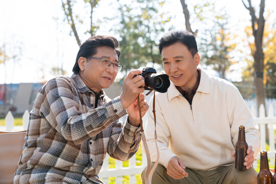 两个老年男人坐在露营地看数码相机