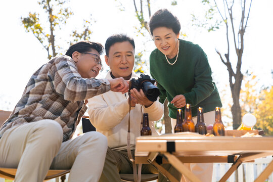 一群中老年人坐在露营地看数码相机