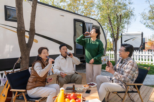 一群中老年人坐在房车露营地喝啤酒聊天