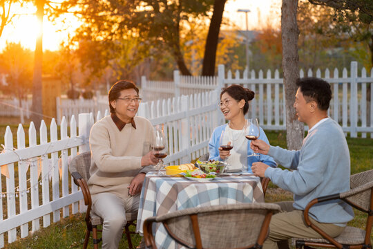 夕阳下中老年朋友在庭院里聚会喝酒聊天