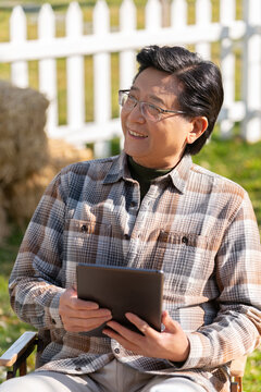 一个老年男人坐在露营院子里看平板电脑