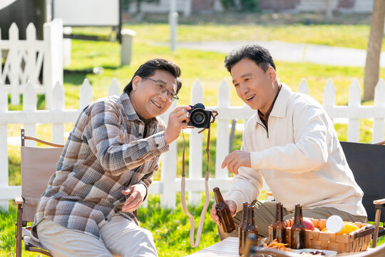 两个老年男人坐在露营地看数码相机