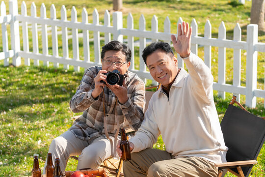 两个老年男人坐在露营地看数码相机