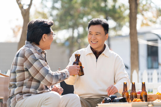 两个老年男人坐在露营地喝啤酒