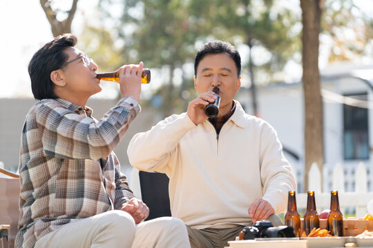 两个老年男人坐在露营地喝啤酒