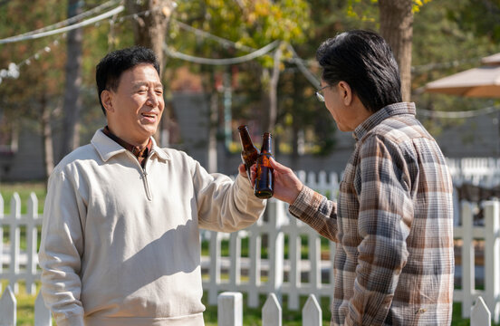 两个老年男人站在露营地喝啤酒