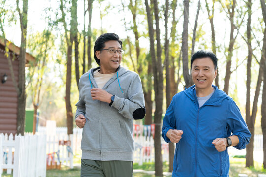 两戴运动手表的中老年男人在树林里跑步健身