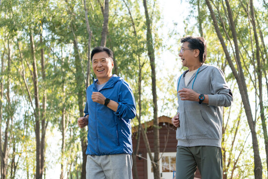 两戴运动手表的中老年男人在树林里跑步健身