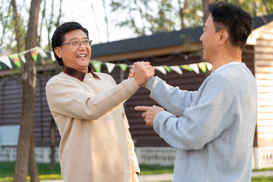 两个中老年男人开心地握手