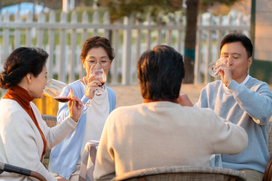 夕阳下中老年朋友在庭院里聚会喝酒聊天