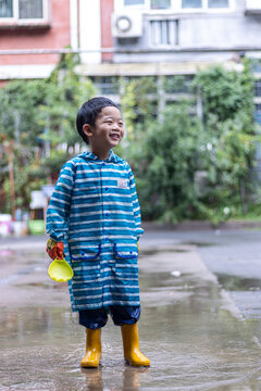 快乐的小男孩雨后在水坑玩耍