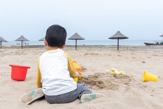 快乐的小男在海边玩沙子