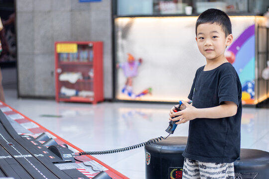 一个小男孩在游戏厅玩赛车玩具