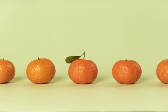五颗排列整齐的橘子绿色背景